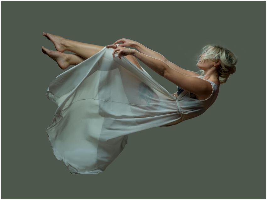 Elegant woman floating mid-air in a sheer dress ag