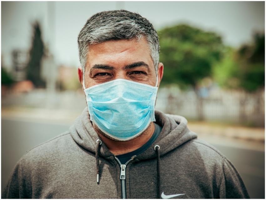 Portrait of a man in a gray hoodie wearing a face