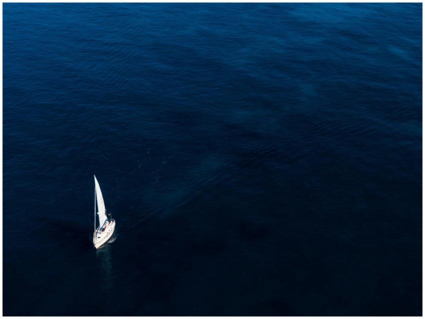 A lone sailboat glides on the vast, blue ocean und