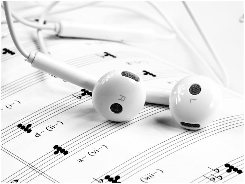 Close-up of white earphones resting on sheet music