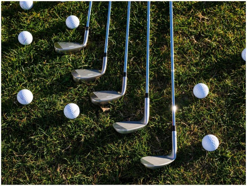 Flat lay of golf clubs and balls arranged on green