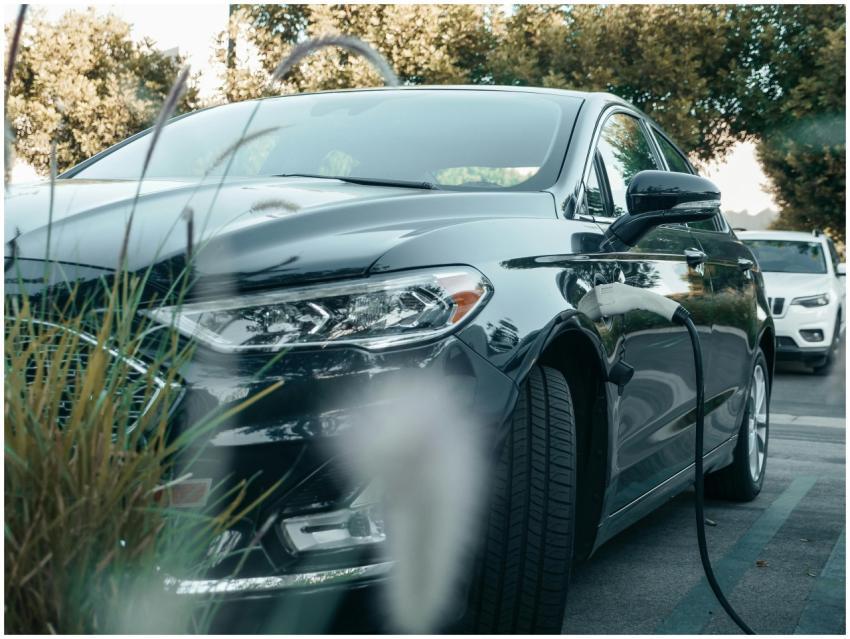 A black hybrid car charging at an outdoor station