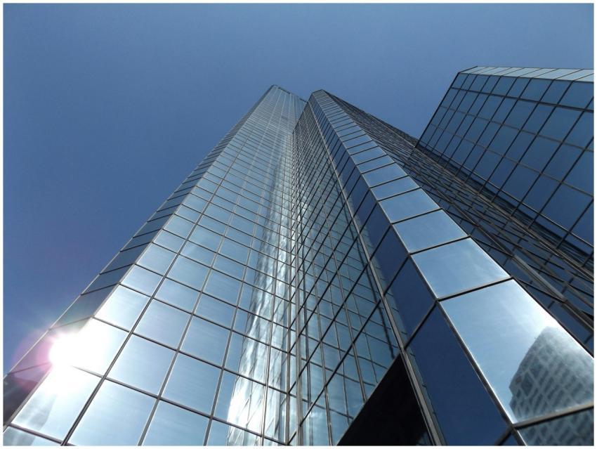 Upward view of a glass skyscraper reflecting the b