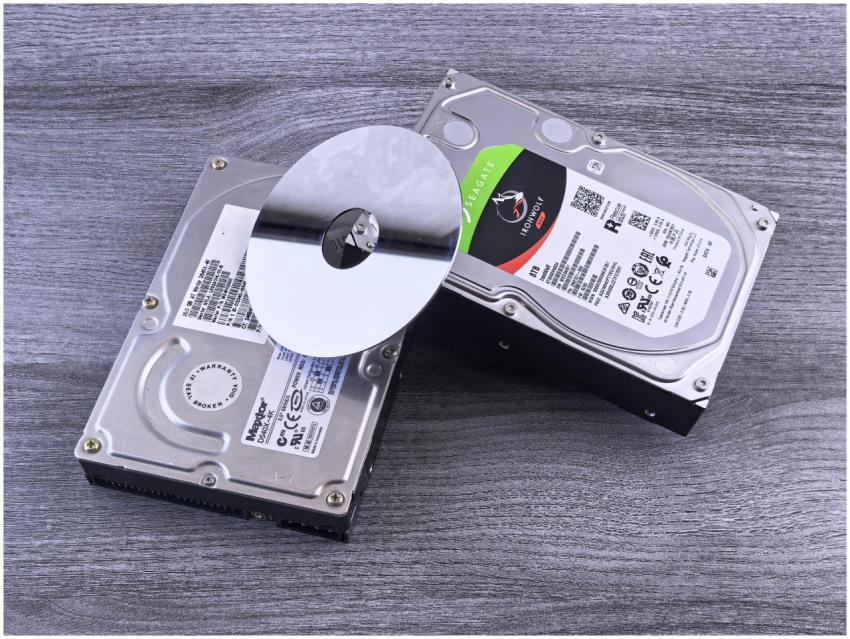 Two computer hard drives and a shiny disk displaye