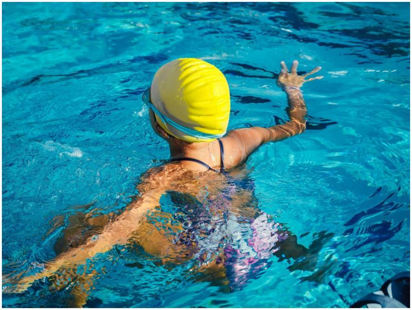 A swimmer wearing a yellow cap enjoying a pool swi
