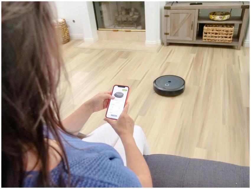 Overhead view of a woman controlling a robot vacuu