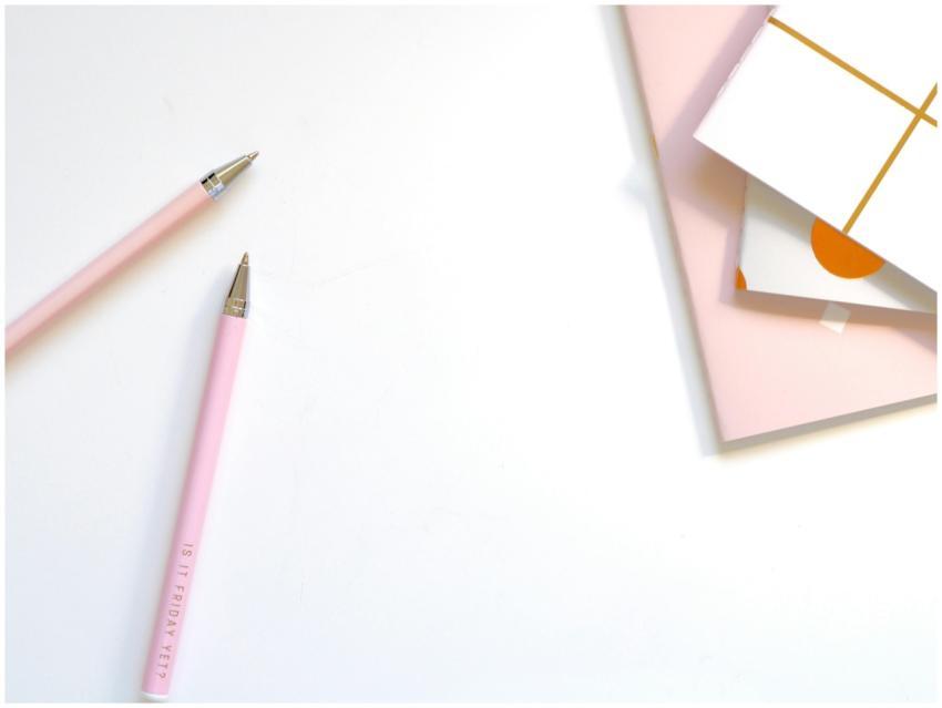 A minimalist flat lay of pink pens and pastel note