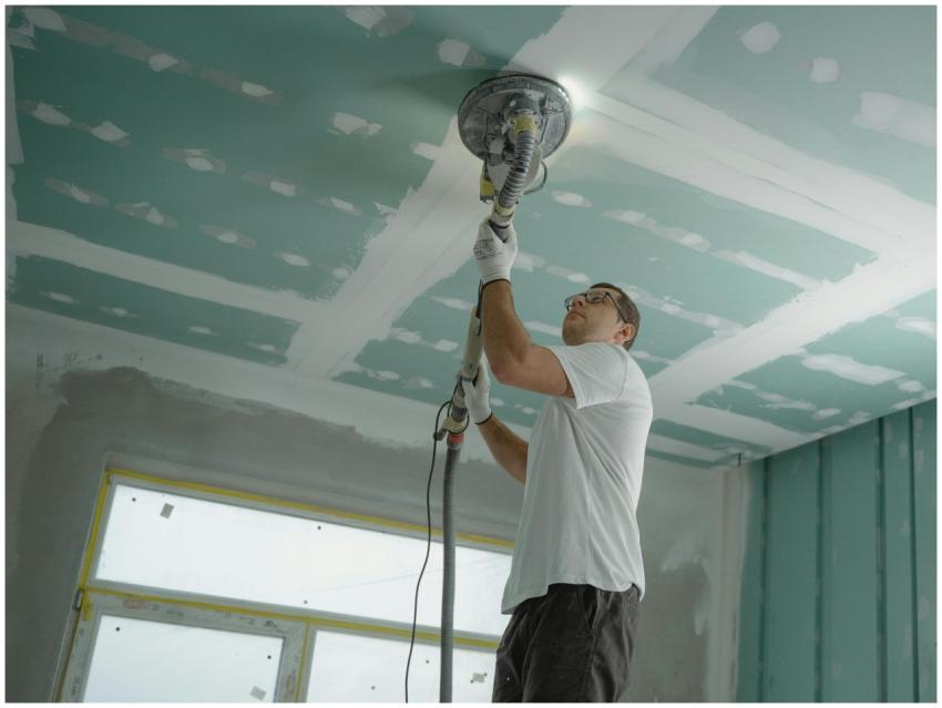 A professional worker sanding the ceiling during a