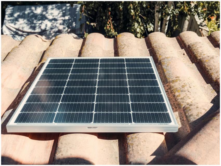 A single solar panel on a rustic tiled roof gleami