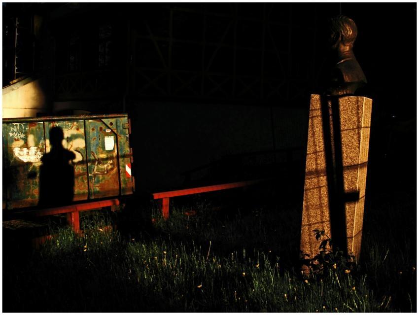 Silhouetted figure casts shadow against a bust in