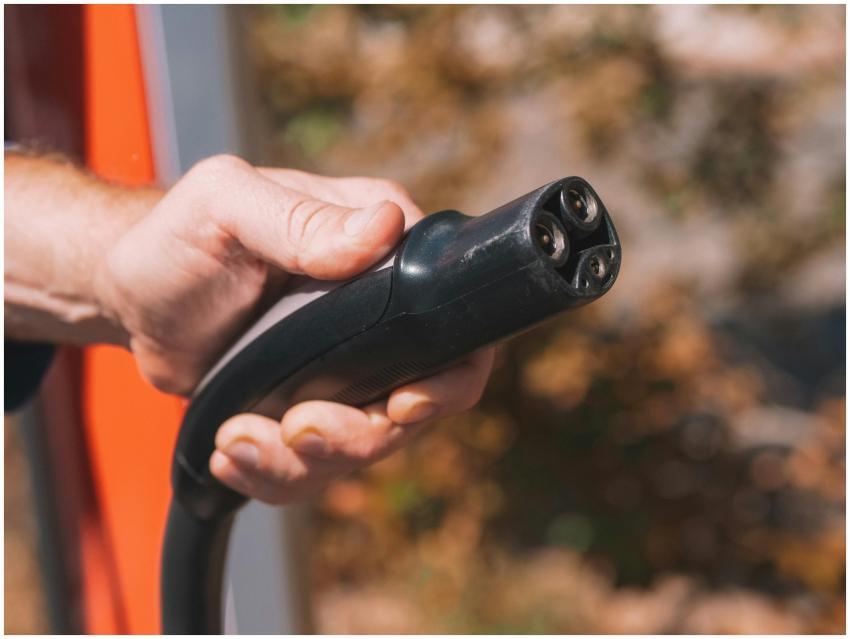 Hand holding an electric vehicle charging plug, sy