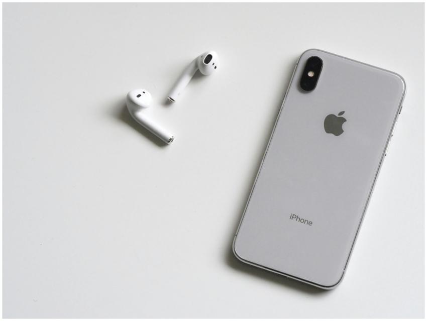 Close-up of a silver iPhone and wireless AirPods o