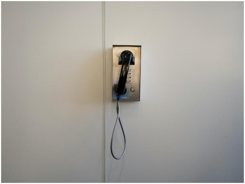 A vintage, wall-mounted payphone in a minimalist s
