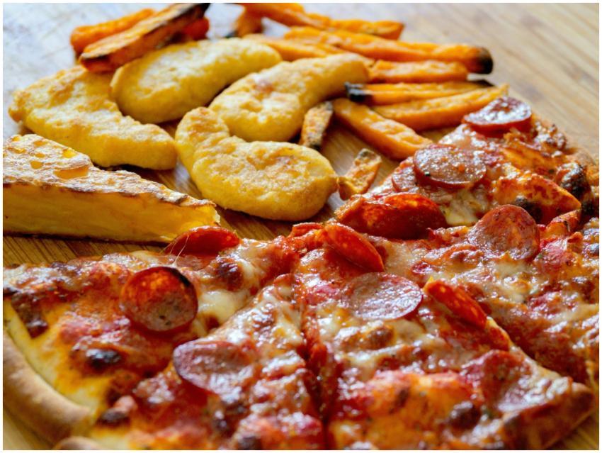 Close-up of diverse fast food including pizza slic