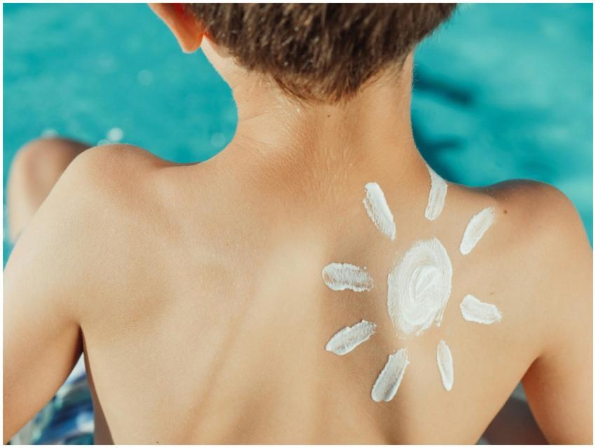 Child's back with sunscreen in sun shape, enjoying