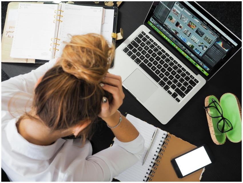 Overhead view of a stressed woman working at a des
