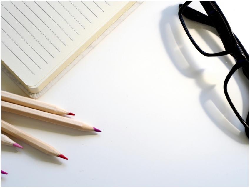 A clean desk setup showing a lined notebook, penci