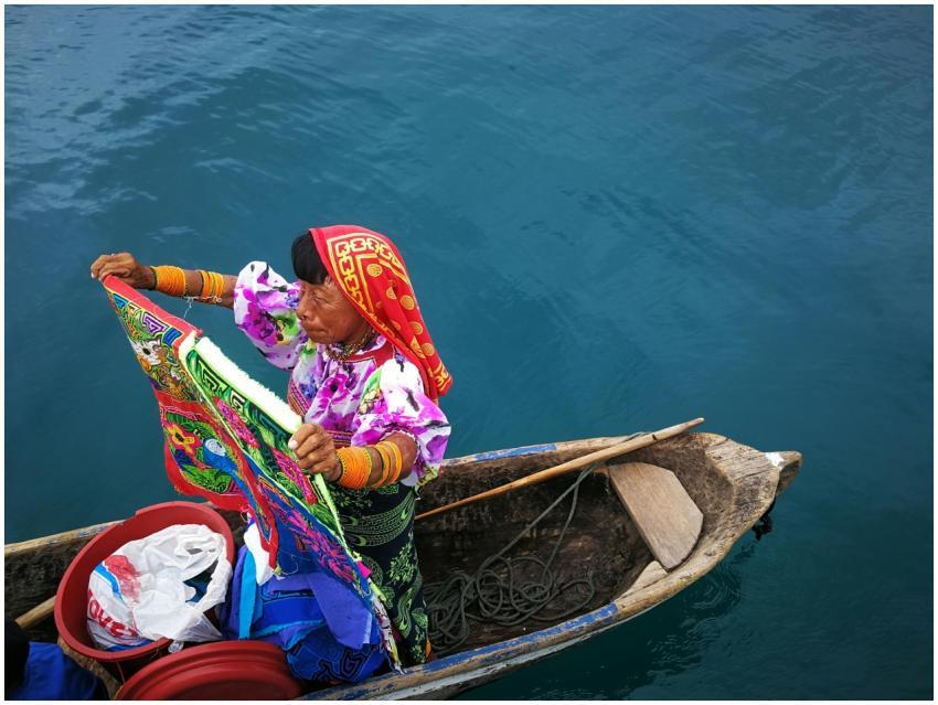 Guna Yala woman in a handcrafted canoe holding col
