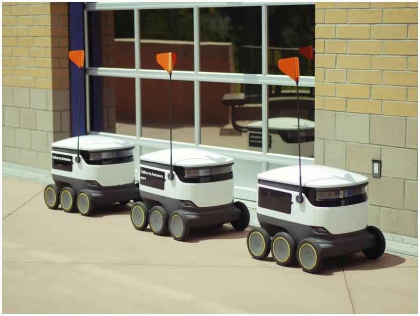 Three autonomous delivery robots parked outside a