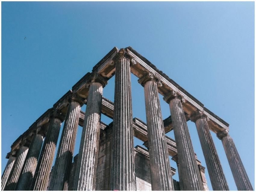 Historic Roman temple columns against a bright blu