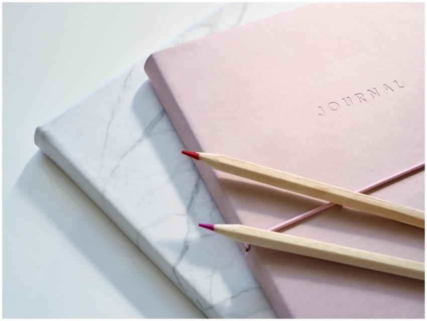 Close-up of a pink journal with pencils on a marbl