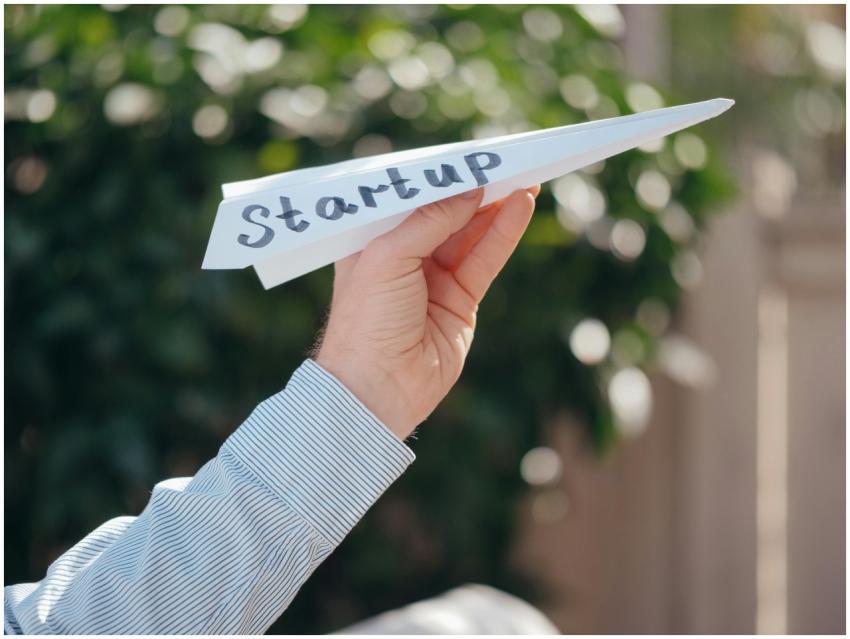 Close-up of a hand holding a paper plane with 'Sta