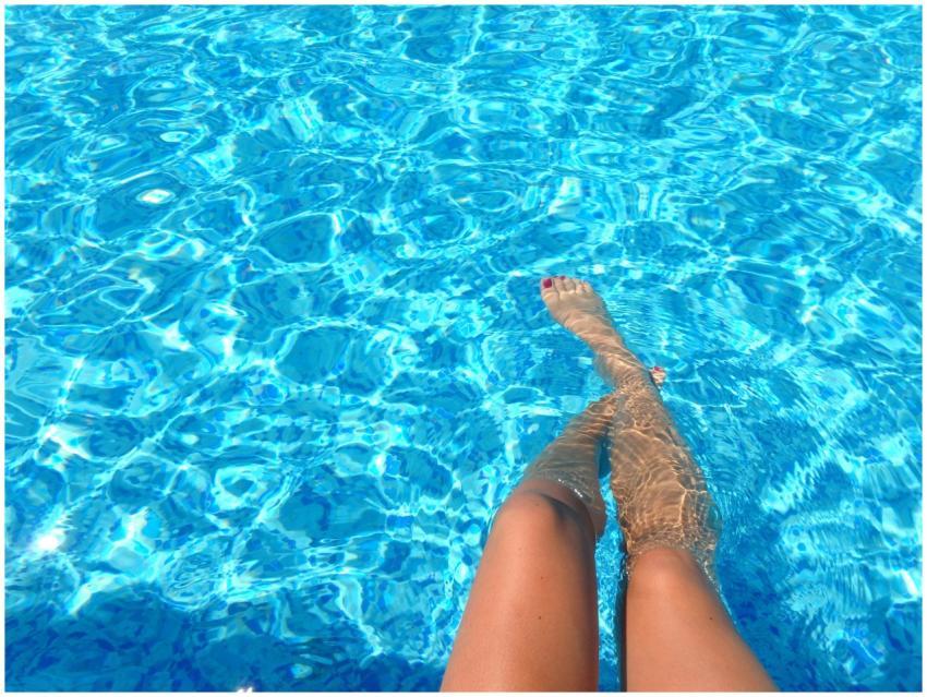 A person relaxes in a swimming pool with clear blu