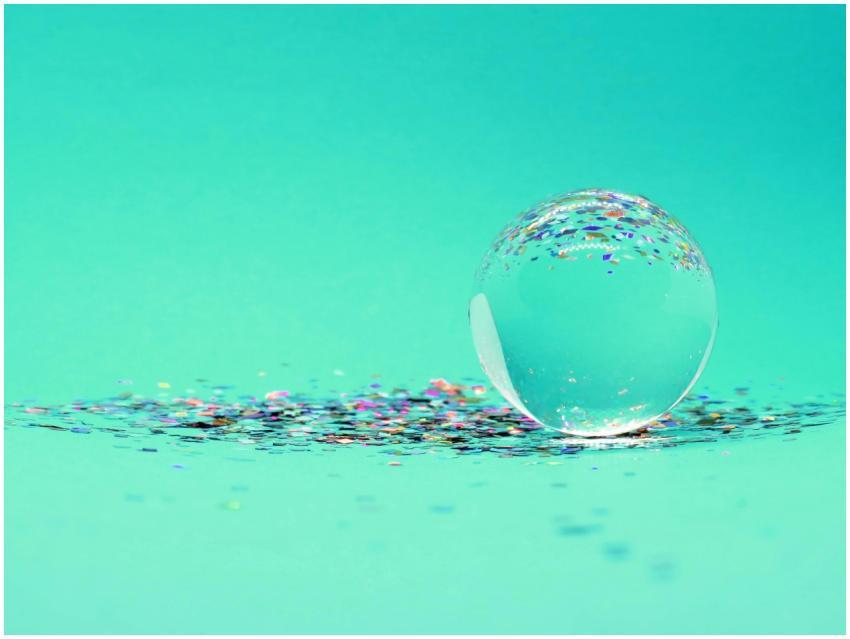 A crystal sphere sits atop colorful glitter on a v