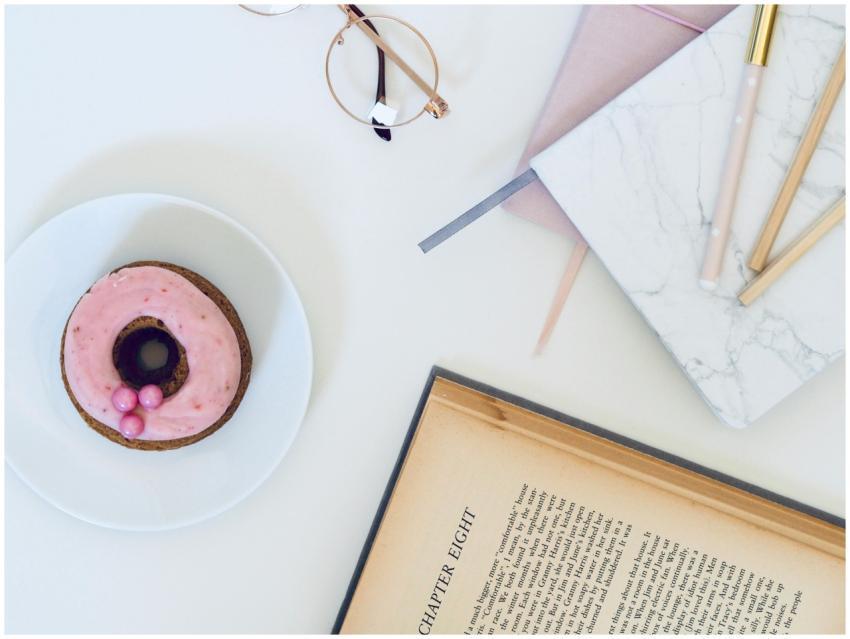 A stylish desk setup with a donut, eyeglasses, boo