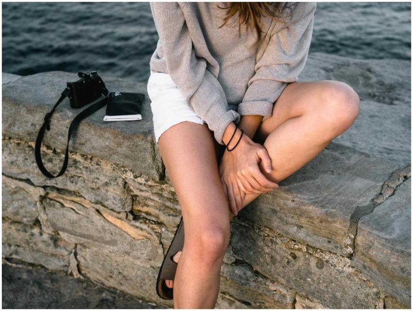 Woman relaxes on a stone wall at Bondi Beach, Aust