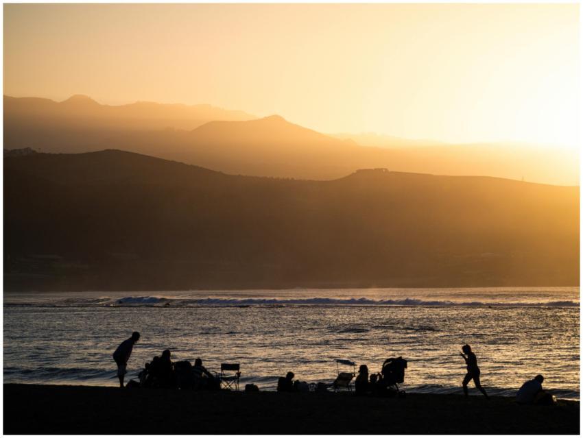 Silhouettes on a beach with mountains and a golden