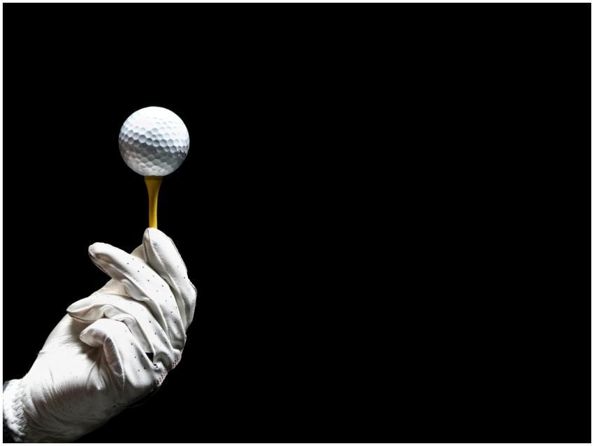 Close-up of a golf ball on a tee held by a gloved
