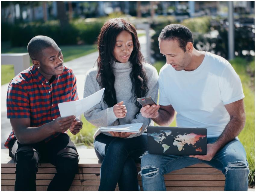 Three colleagues collaborating outside with laptop