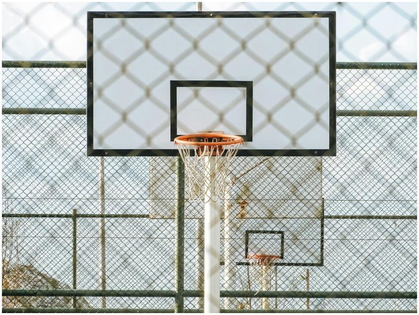 A basketball hoop seen through a chainlink fence o