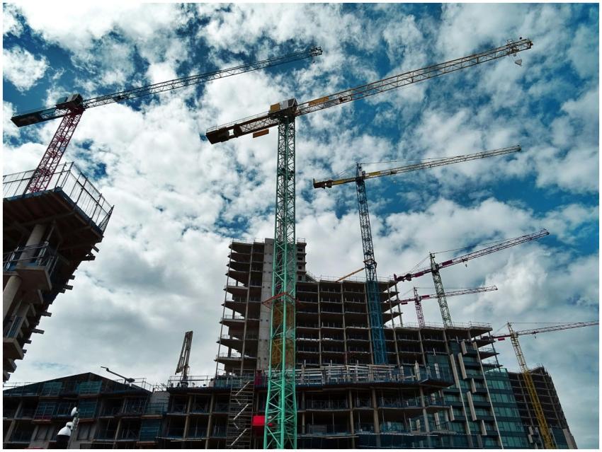 Urban construction site with numerous cranes frami