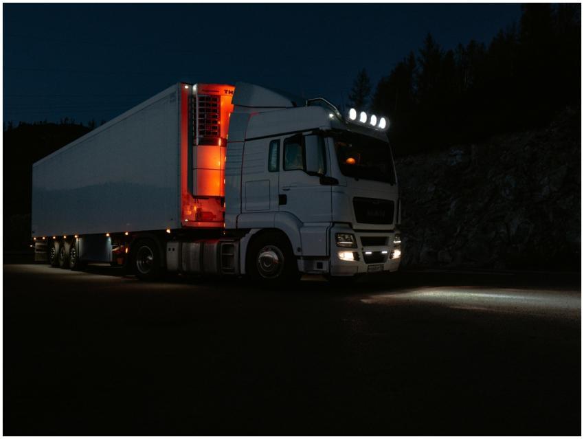 A white truck lit by headlights and interior light