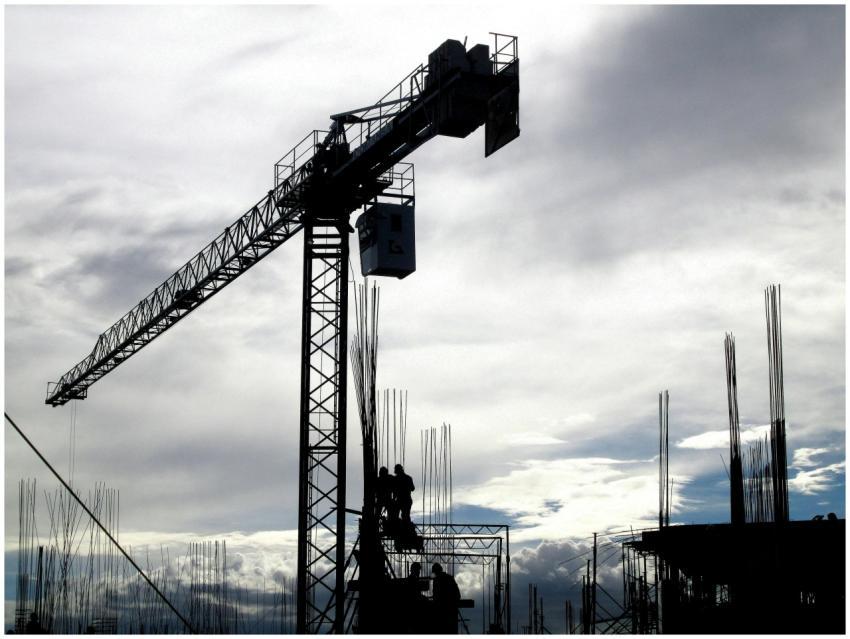 Silhouetted construction crane and workers against