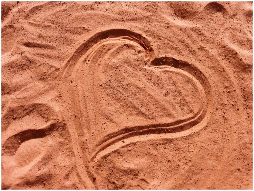 Heart shape drawn in soft sand, captured under sun