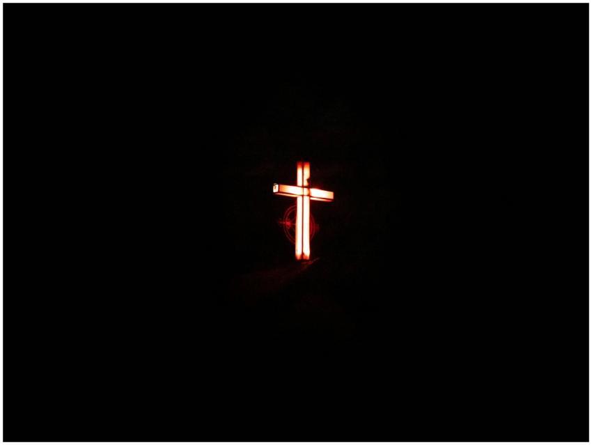 Glowing cross against a dark background from Faisa