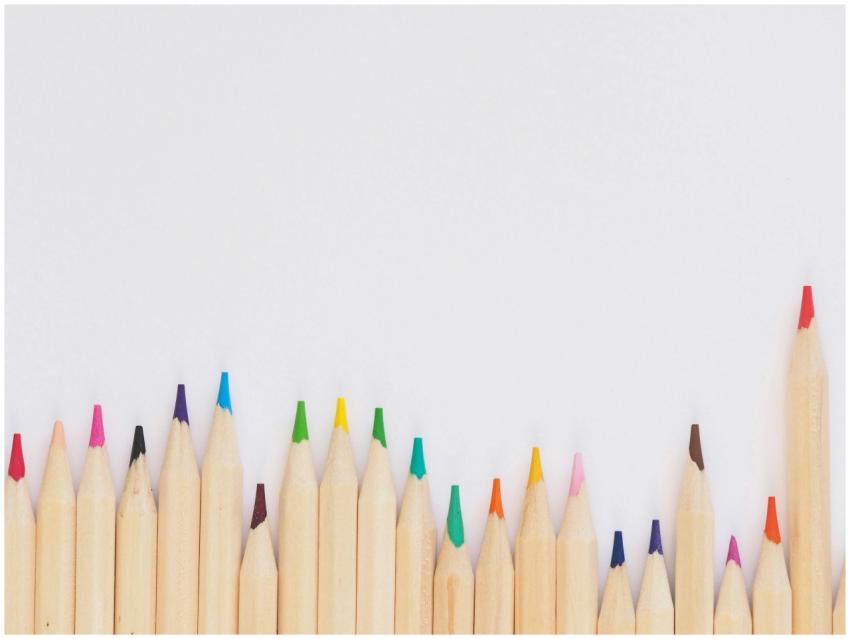 A row of vibrant colored pencils aligned on a whit