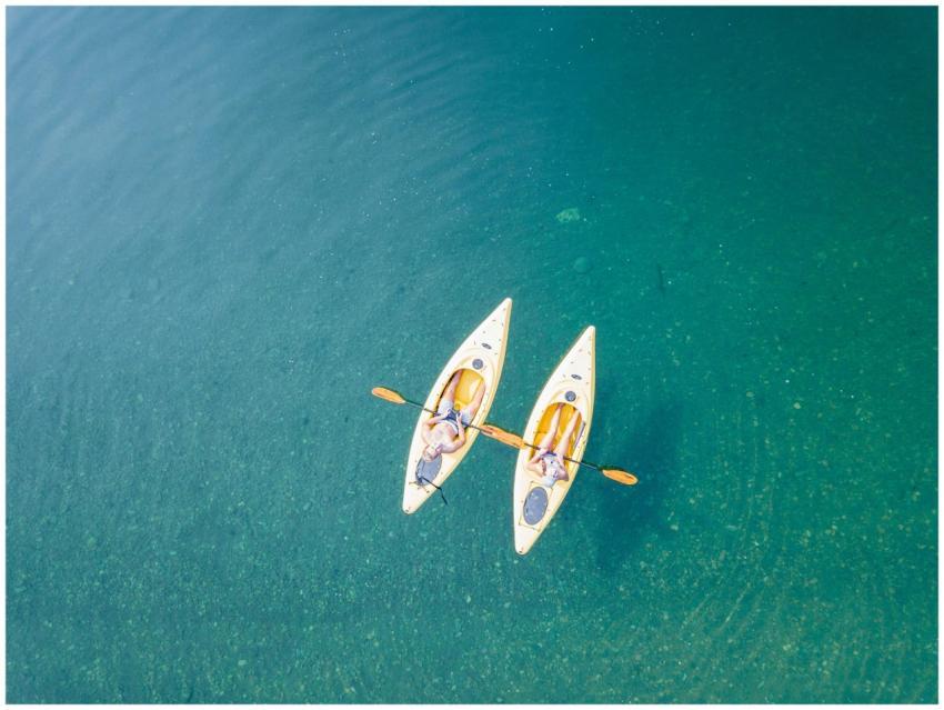 Aerial shot of two people kayaking on clear, turqu