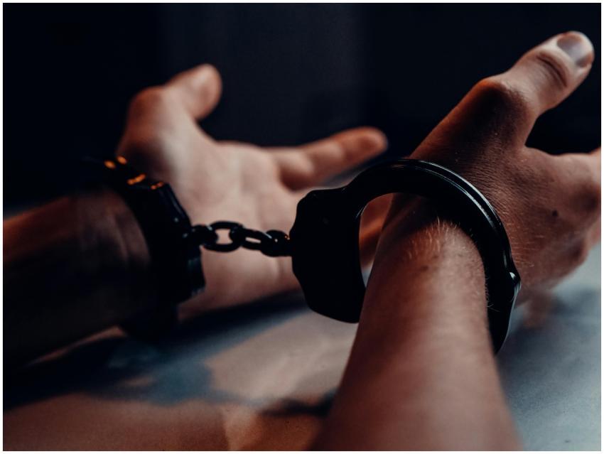 A close-up of human hands handcuffed on a table wi