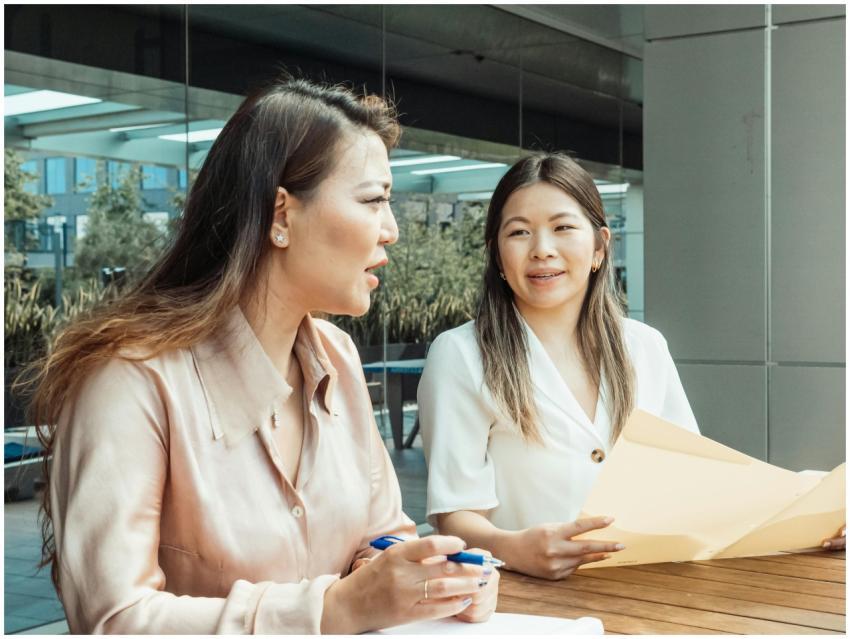 Two women discussing business plans outdoors with