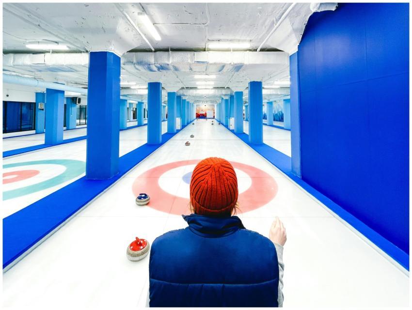 Back view of a person in a hat on an indoor curlin