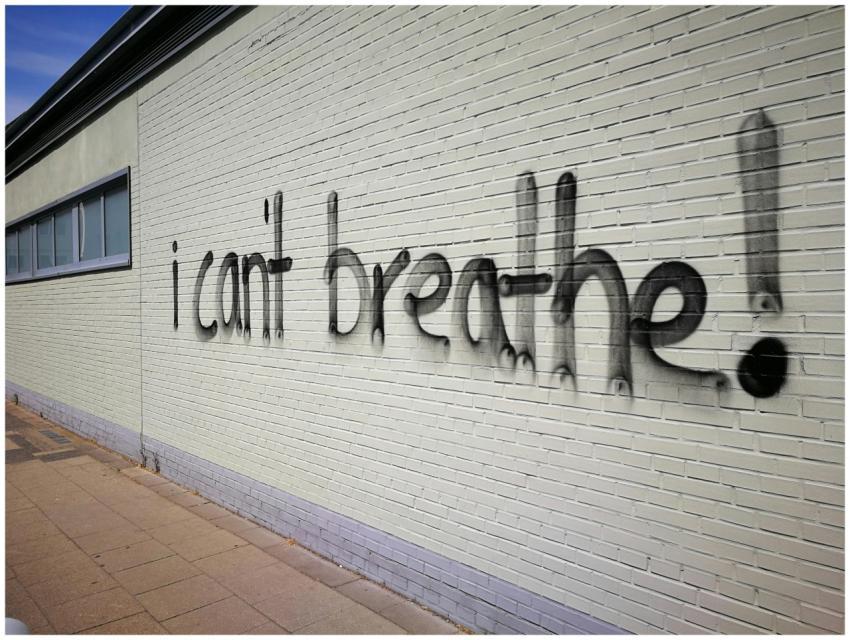 Graffiti text 'I can't breathe' on a brick wall, s