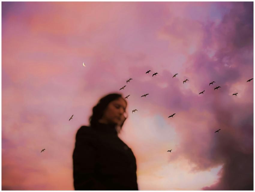 Blurry silhouette of person with birds flying and