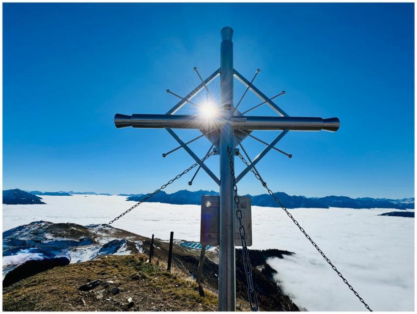 Sunburst through mountain summit cross overlooking