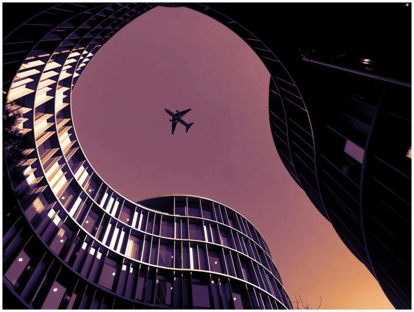 Low-angle shot of airplane over modern skyscrapers