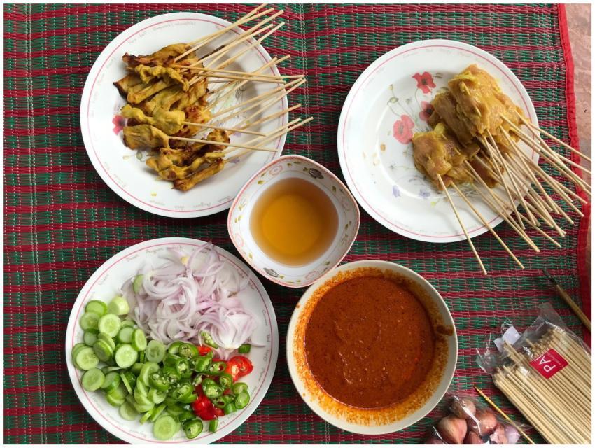 Top view of chicken satay skewers with spicy sauce