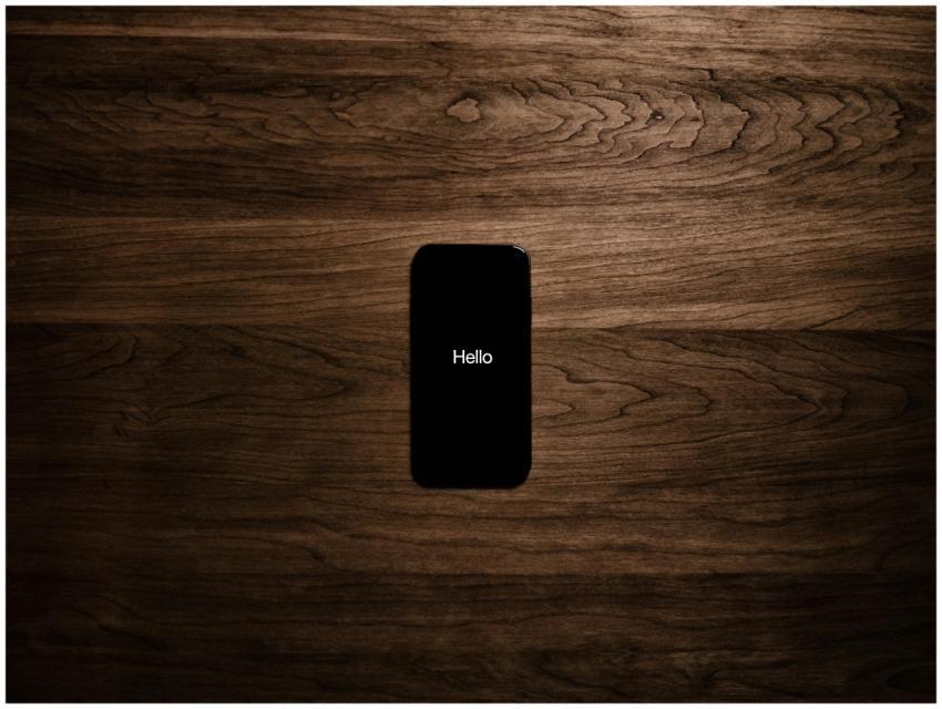 A smartphone displays 'Hello' against a dark woode